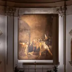 Il Seppellimento di Santa Lucia, capolavoro di Caravaggio in Sicilia, illuminato nell'oscurità di una chiesa.