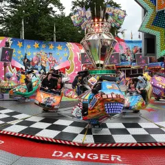 Bunte Fahrgeschäfte drehen sich auf der Kirmes Bergneustadt. Menschen lachen und genießen die Fahrt.