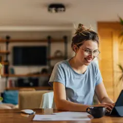 Uśmiechnięta kobieta w okularach pracuje na tablecie, być może przedłuża umowę.