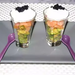 Deux verrines avocat saumon, garnies de crème et de caviar, prêtes à être dégustées avec leurs cuillères violettes.