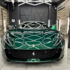 Zielone Ferrari po nałożeniu ceramiki na auto. Lśniący lakier odbija światła studia detailingowego.