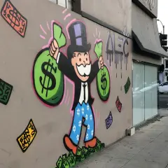 A vibrant graffiti drawing of the Monopoly Man, clutching bags of money, stands proudly on a wall. Dollar bills rain down around him, a testament to his wealth.