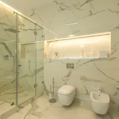 Nowoczesna łazienka z prysznicem walk-in i wanną. Ściany i podłoga wykończone wielkoformatowymi płytkami imitującymi marmur. Eleganckie rozwiązanie co zamiast płytek pod prysznic.