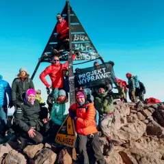 Grupa zdobywców na szczycie w Maroku, z flagą "Projekt Wyprawa". Warto zobaczyć to miejsce!