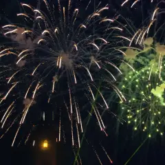 Pokaz sztucznych ogni nad ciemnym niebem, z widocznym fragmentem wieży.