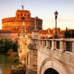 Le pont Saint-Ange à Rome, orné de statues d'anges, mène au château Saint-Ange au coucher du soleil.