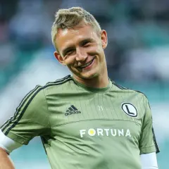Uśmiechnięty Kuba Rzeźniczak w zielonej koszulce treningowej z logo Legii Warszawa i napisem Fortuna.