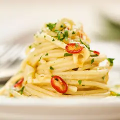 Ein Teller Spaghetti Aglio e Olio, garniert mit Petersilie und Chilischeiben. Ein Klassiker der besten italienischen Pasta Rezepte.
