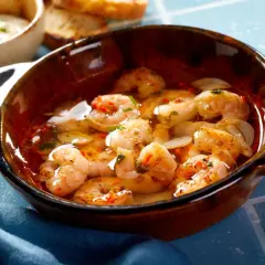 En skål med saftiga gambas pil pil, simmande i vitlök och chiliolja, redo att avnjutas med rostat bröd.