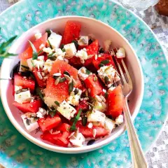 Insalata anguria e feta, fresca e colorata, con semi di girasole e zucca, guarnita con erbe aromatiche. Perfetta per l'estate.