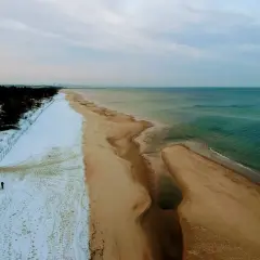 Plaża nad Bałtykiem zimą: śnieg, piasek i turkusowa woda.