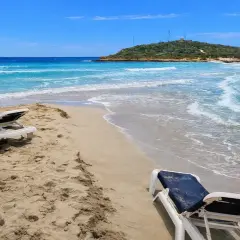 Plaża na Cyprze w styczniu. Dwa puste leżaki czekają na plaży, a turkusowe morze delikatnie faluje.