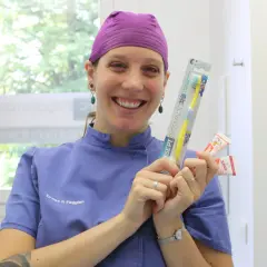 Sorriso di un dentista che mostra spazzolino e dentifrici per la pulizia dei denti bambini.