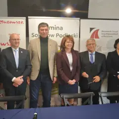 Grupa osób pozuje do zdjęcia na tle banerów informujących o budowie obwodnicy Sokołowa Podlaskiego.