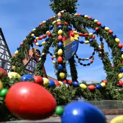 Bunte Ostereier schmücken einen Tannenkranz vor Fachwerkhäusern. Es gibt Karsamstag, die Vorfreude auf Ostern ist spürbar.