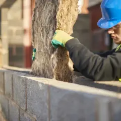 Operaio con casco blu installa isolante. Potrebbe considerare i cappotto termico svantaggi, come la difficoltà di posa.