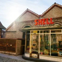 Retro Shell-Tankstelle im Motorworld Metzingen, mit Fachwerkhaus im Hintergrund.