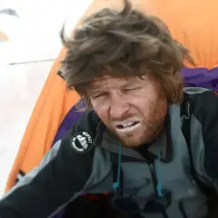 Zmęczony alpinista w namiocie, z białym nalotem na ustach, cierpi na chorobę górską.