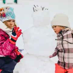 Bambini creano un pupazzo di neve in montagna, un vero natale in montagna con bambini che si divertono nella neve.