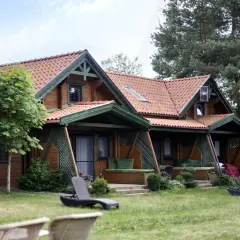 Drewniany domek spa na Mazurach, otoczony zielenią. Leżaki zapraszają do relaksu.