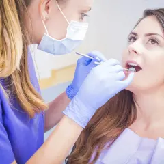 Dentystka bada jamę ustną pacjentki, szukając ewentualnych zmian.