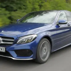 Niebieski Mercedes-Benz c205 w ruchu, z rozmytym tłem zieleni i drogi.