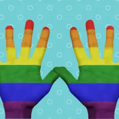 Tęczowe rysunki na ręce, symbolizujące dumę i akceptację, unoszą się na błękitnym tle z białymi kółkami.