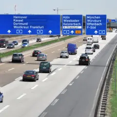 Autostrada w Niemczech z tablicami kierunkowymi do Kolonii, Frankfurtu i Monachium. Pytanie: czy w Niemczech są płatne autostrady?