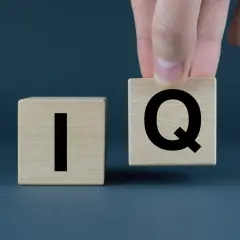 Dłoń układa kostkę z literą "Q" obok kostki z literą "I". Co to jest IQ?