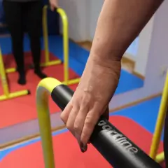 Rehabilitacja po niedowładzie nóg: ćwiczenia na poręczach. Dłoń trzymająca uchwyt.