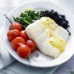Filet de poisson blanc nappé de sauce safranée, accompagné de tomates cerises rôties, d'épinards et de riz noir. Une belle recette de turbot.