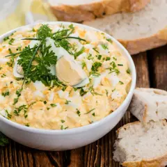Pyszna pasta z jajek, udekorowana natką pietruszki i jajkiem na twardo, podana z chlebem.