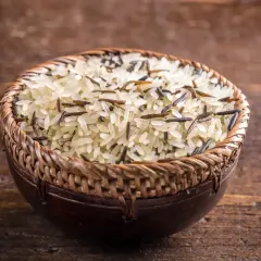 Mieszanka ryżu basmati i dzikiego ryżu w plecionej misce na drewnianym tle.