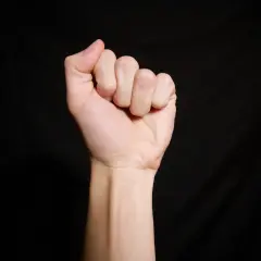 Zaciśnięta pięść z widocznymi krótkimi palcami, co może sugerować brachydaktylię.