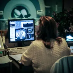 Kobieta analizuje obrazy z rezonansu magnetycznego na monitorze w pracowni medycznej.