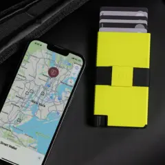 Ein Smartphone mit Karte von New York und ein gelbes Kartenetui liegen neben einem schwarzen Rucksack. Perfekt, um bargeldlos zu bezahlen.