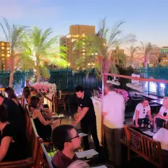 Un rooftop bar a New York City, con persone che si godono la vita notturna tra palme e luci della città.