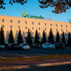 Façade de l'hôtel Campanile Guéret avec parking et arbres.