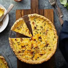 Une quiche au bacon et fromage, parfaite pour une recette quiche facile. Une part est déjà servie avec du bacon croustillant.