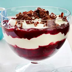 Schichtdessert mit Kirschen und einer luftigen Creme aus Mascarpone, garniert mit Schokoladenlocken.