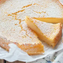 Deliziosa torta ricotta e limone, soffice e spolverata di zucchero a velo, con una fetta tagliata.