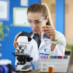 Studentka na biotechnologia studia bada próbkę pod mikroskopem.