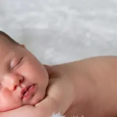 Śpiące, 3 miesięczne dziecko z delikatnymi włoskami, wtulone w miękkie futerko.