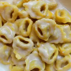 Tortellini freschi immersi in una cremosa fonduta di parmigiano, un abbraccio di sapore.