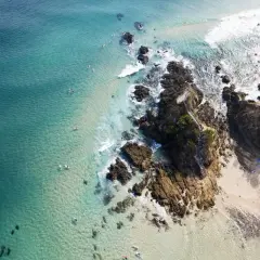 Türkisblaues Meer, Surfer und felsige Küsten – ein Bild von traum reiseziele, das zum Träumen einlädt.