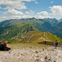 Grupa turystów na tle malowniczych górskich szlaków w Tatrach.