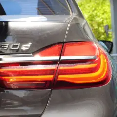 Tylna część lśniącego BMW 730d z włączonymi światłami stopu.