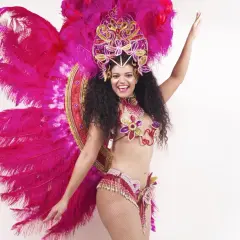 Uśmiechnięta tancerka w barwnym stroju z piórami, gotowa do wykonania energicznych samba kroki.