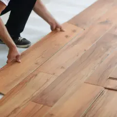 Hands installing laminate flooring. Is laminate flooring hard to install? This DIY project looks manageable.