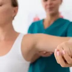 Fizjoterapeuta pomaga pacjentce z zespołem skrzyżowania dolnego w ćwiczeniach ramienia.